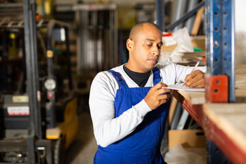 Confident hispanic worker taking inventory of goods in building materials store