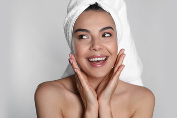 Beautiful young woman with towel on head against light background