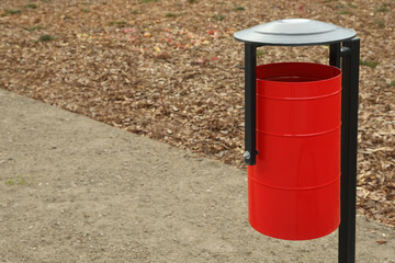 Red metal trash bin outdoors. Space for text