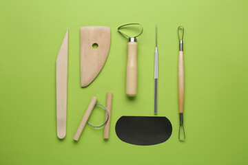 Set of clay modeling tools on green background, flat lay
