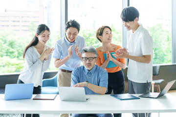 Obraz premium パソコンを見ながら拍手をするビジネスパーソン