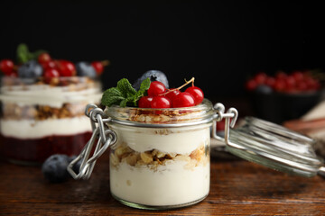 Delicious yogurt parfait with fresh berries and mint on wooden table, closeup