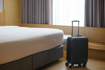 A large black suitcase sits at the foot of the bed in a luxury hotel.