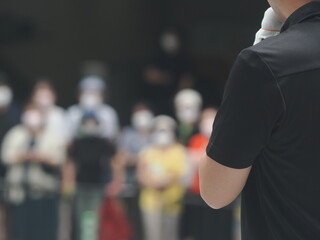 駅前で街頭演説する人とコロナ渦のためマスクをしている聴衆