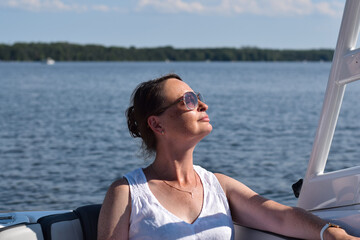 Middle aged woman enjoying sunshine on boat on a lake