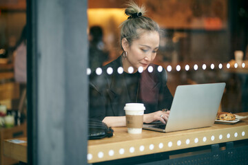mature asian businesswoman working in coffee shop using laptop computer