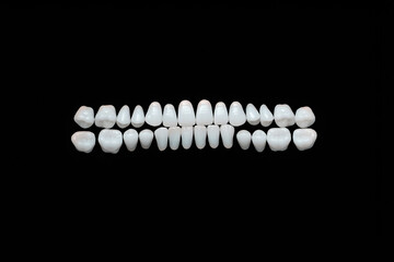 a row of white dentures on a black background. teeth