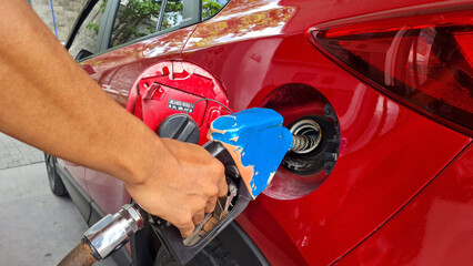 Refuel cars at the fuel pump. The driver hands, refuel and pump the car's gasoline with fuel at the...