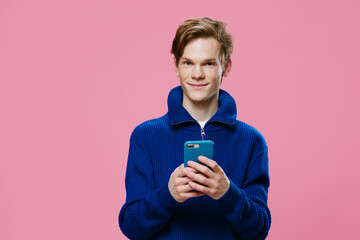 a handsome red-haired guy stands with a phone in a blue case in his hands and smiles cutely at the camera