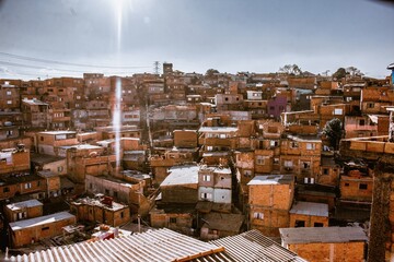 urbanism and architecture of the favelas of brazil, underdeveloped country, several houses with clear skies and rising sun