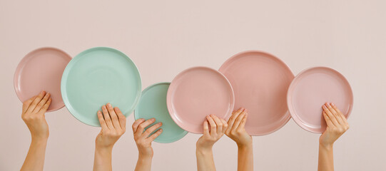 Hands with different clean plates on beige background