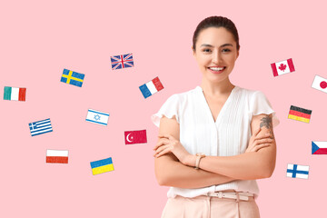 Beautiful young woman and different flags on pink background. Studying of foreign languages