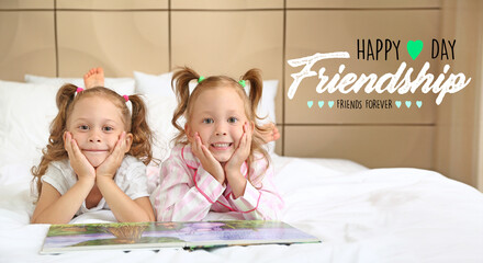 Adorable little girls with book in bedroom. Happy Friendship Day