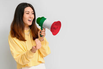 Young Asian woman with megaphone on light background. Concept of studying Italian language