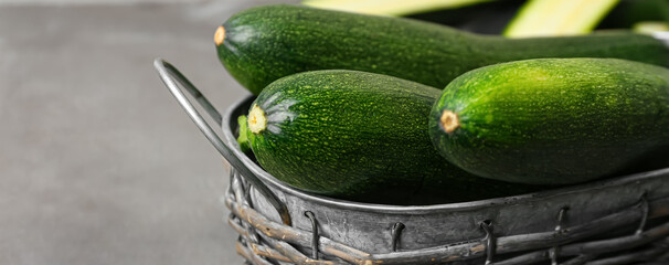 Basket with fresh zucchini on grey background, closeup