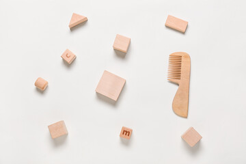 Wooden hair comb for baby and scattered cubes on white background