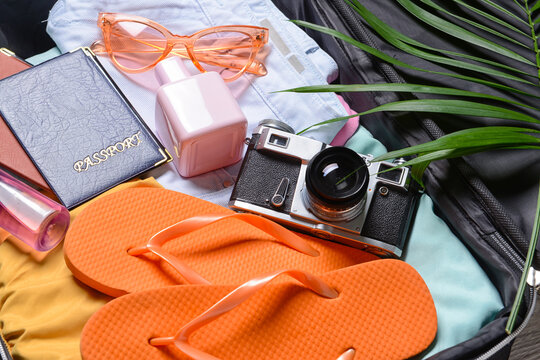 Female accessories for travelling and photo camera in opened suitcase, closeup