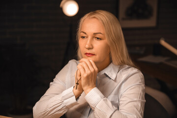 Religious mature woman praying in dark room