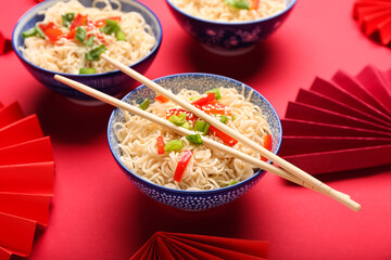 Bowls of tasty noodles on red background