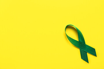 Green ribbon on yellow background. Liver cancer concept