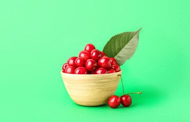 Bowl of sweet ripe cherries on green background