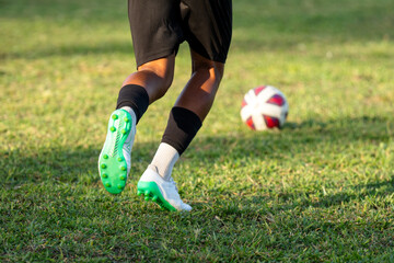 outdoor soccer player kicking a football on a grass sport field