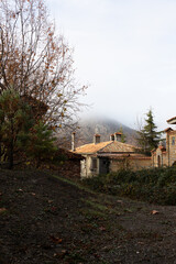 Fototapeta na wymiar A beautiful old house in the foothills. Cozy dwelling, autumn forest and mountain fog. Vertical photo.