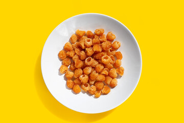 Dried longan in white plate on yellow background.