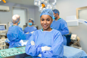 Close-up of a African American surgeon woman looking at camera with colleagues performing in...