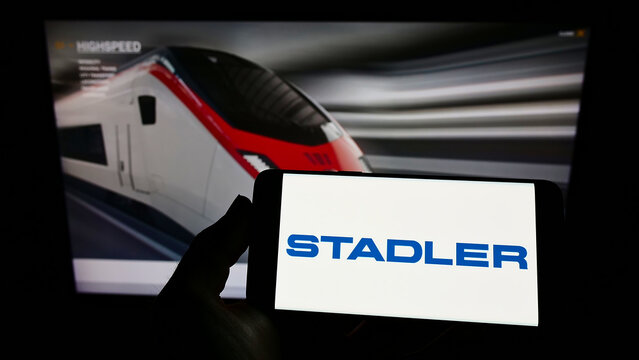 Stuttgart, Germany - 01-16-2022: Person holding mobile phone with logo of Swiss company Stadler Rail AG on screen in front of business web page. Focus on phone display.