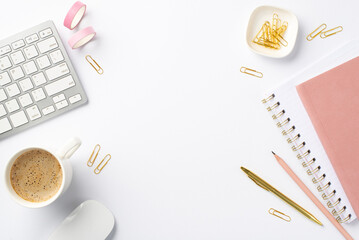 Business concept. Top view photo of workplace keyboard computer mouse cup of coffee stationery pink adhesive tape clips pens and pink planners on isolated white background with empty space