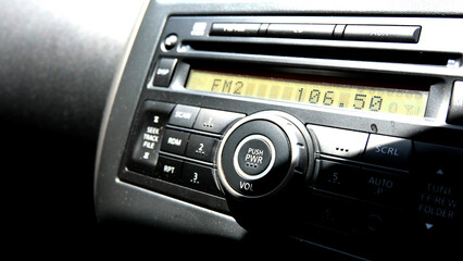 Women turning button on car radio for listening to music