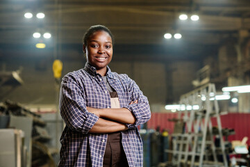Portrait of African female worker in workwear standing with her arms crossed and smiling at camera