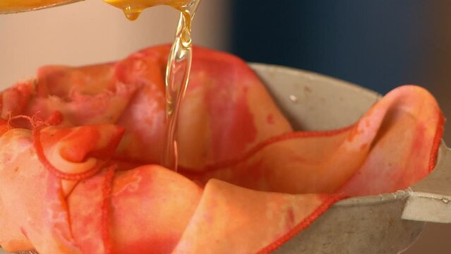 Pouring babassu vegetable oil into a siphon and cloth to filter it for use