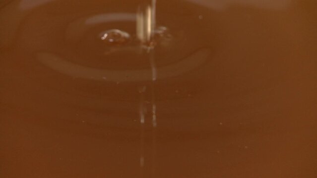 Babassu oil from palm tree seeds dripping into a vat of processed vegetable oil