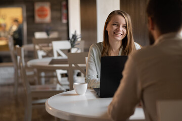 Young couple working on laptop in cafe. Handsome young man and attractive woman are spending time together. Coworking and freelance