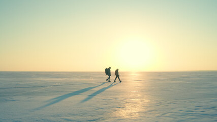 The two people with backpacks going through the snow field © Artem