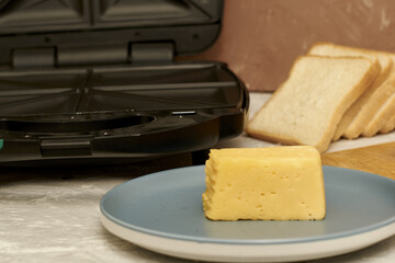 sandwich maker cheese sausage and bread on the table
