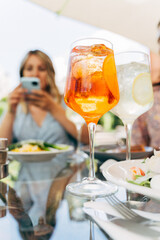 Colorful iced cocktails on dinner table. Group of friends having a meal outdoors