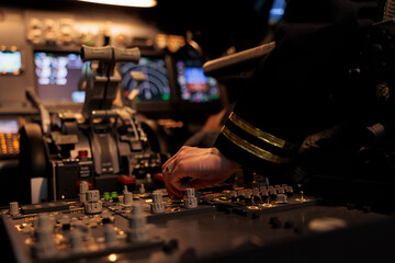 Woman aircrew switching control panel buttons on dashboard command, using radar compass on windscreen in cockpit cabin. Copilot flying plane jet with travel navigation. Close up.