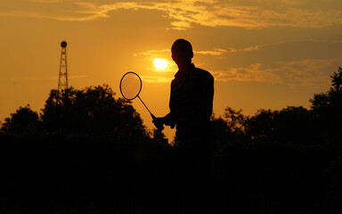 silhouettes Man is holding the shuttlecock and the badminton racket