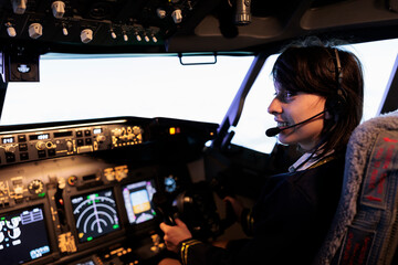 Aircrew member flying plane from cockpit with dashboard command and control panel, using steering...