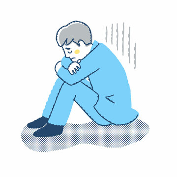 膝を抱えて落ち込んでいる男性