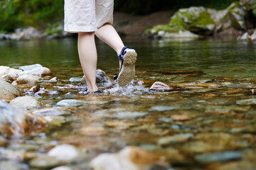 川に浸かる若い女性の足元