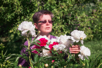 Woman in a garden with peonies collects a bouquet