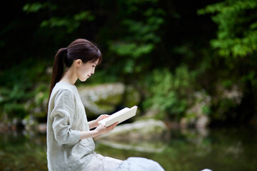 自然の中で読書をする日本人女性