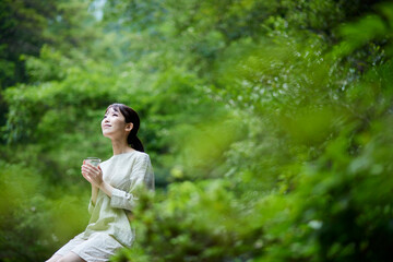 自然の中でコップに入った水を持つ女性