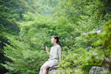 Naklejka na ściany i meble 自然の中でスマートフォンを持つ若い日本人女性