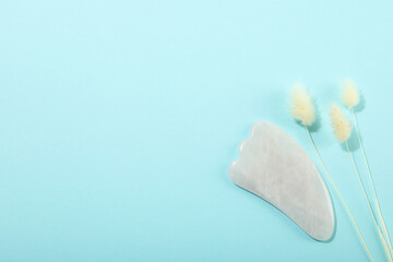 Lifting and toning treatment concept with gua sha on blue background