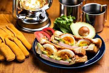 木製のテーブルにホットサンドとコーヒーとランタンのキャンプ飯